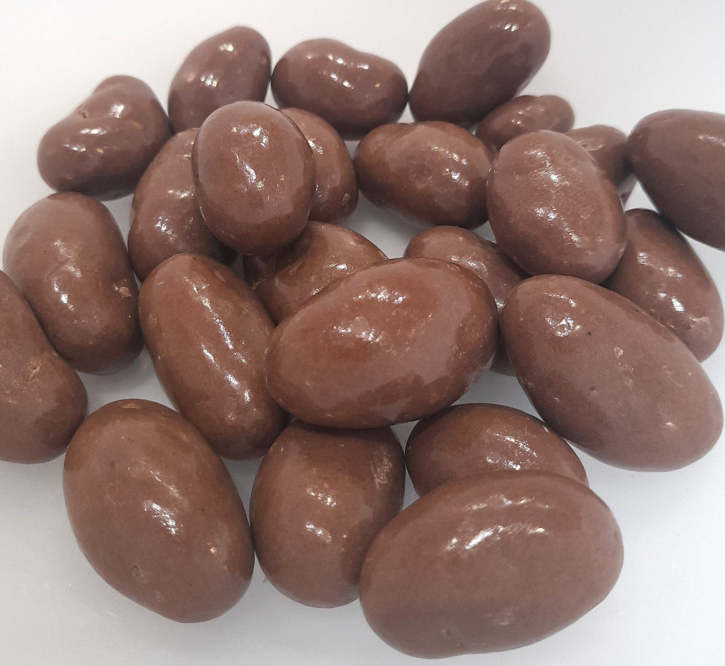 A bowl of milk chocolate covered Brazil nuts.