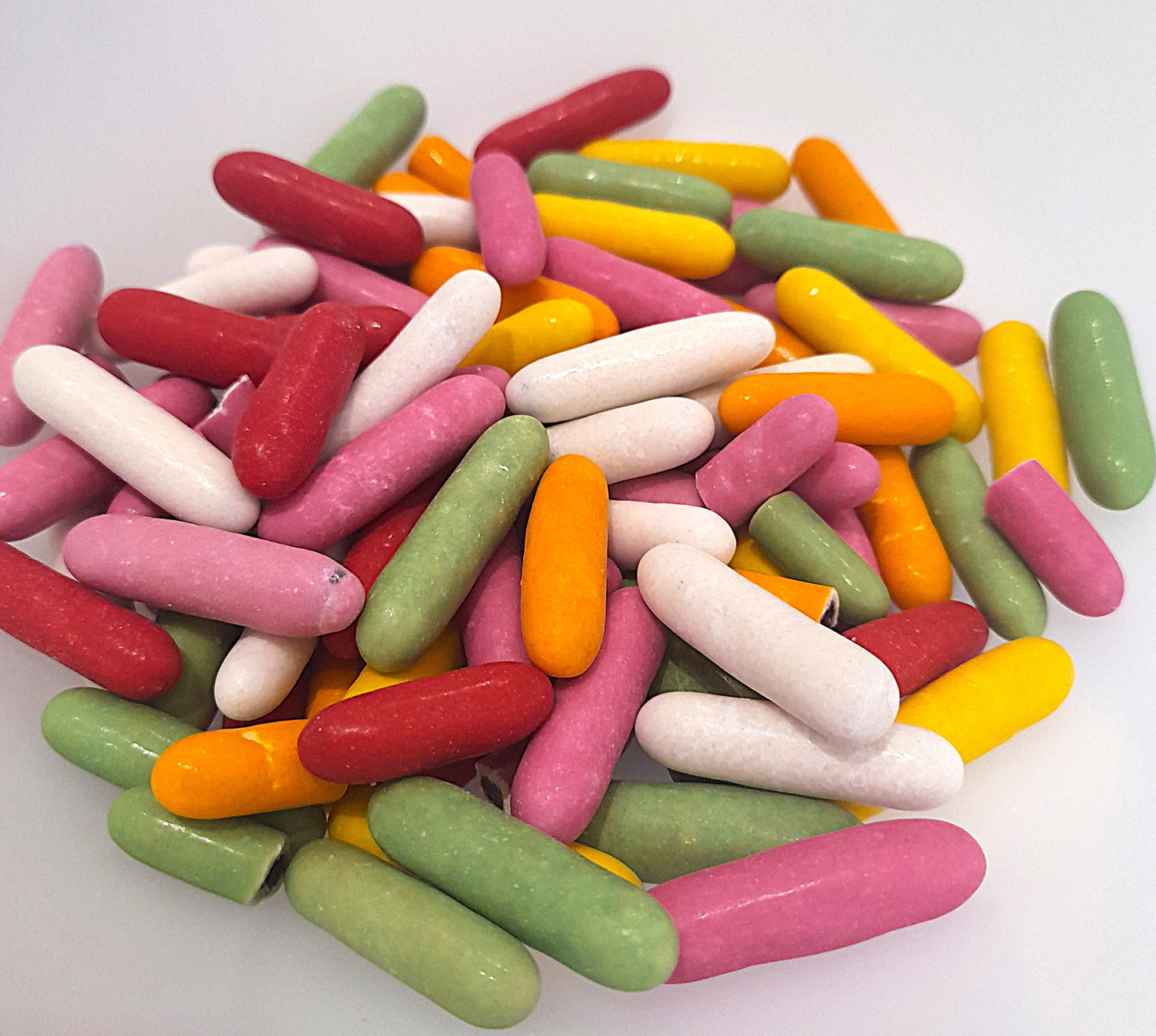 A collection of colorful liquorice comfits in red, yellow, green, and pink, arranged in a pile.