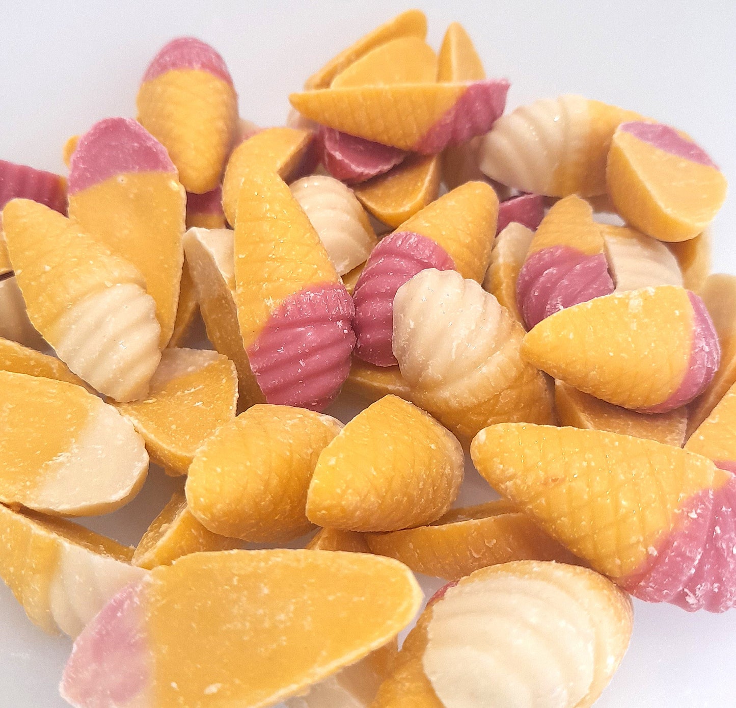 A group of strawberry and vanilla flavored candy cones with yellow and pink coloring, resembling small ice cream cones.