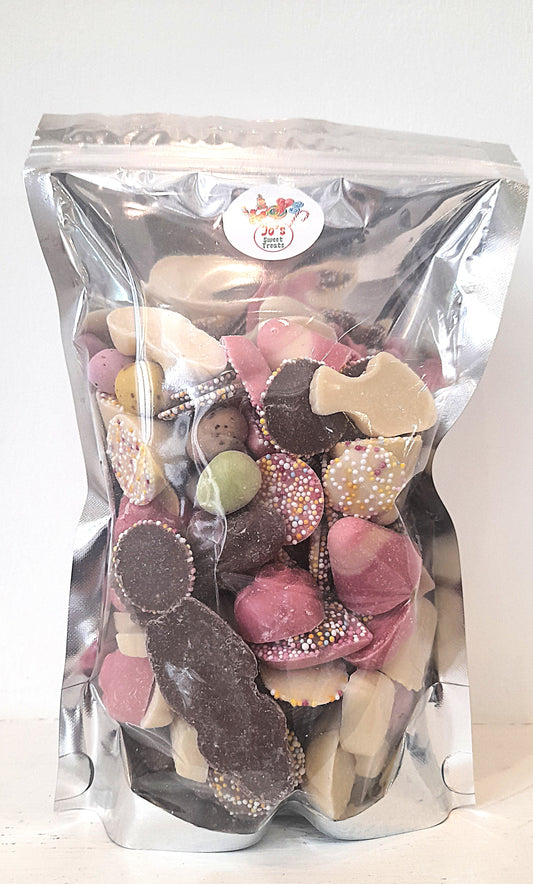 A clear plastic bag filled with various shapes of chocolate pieces, including hearts, circles, and other candies. The bag is labeled with the brand 'Jo's Sweet Treats'.