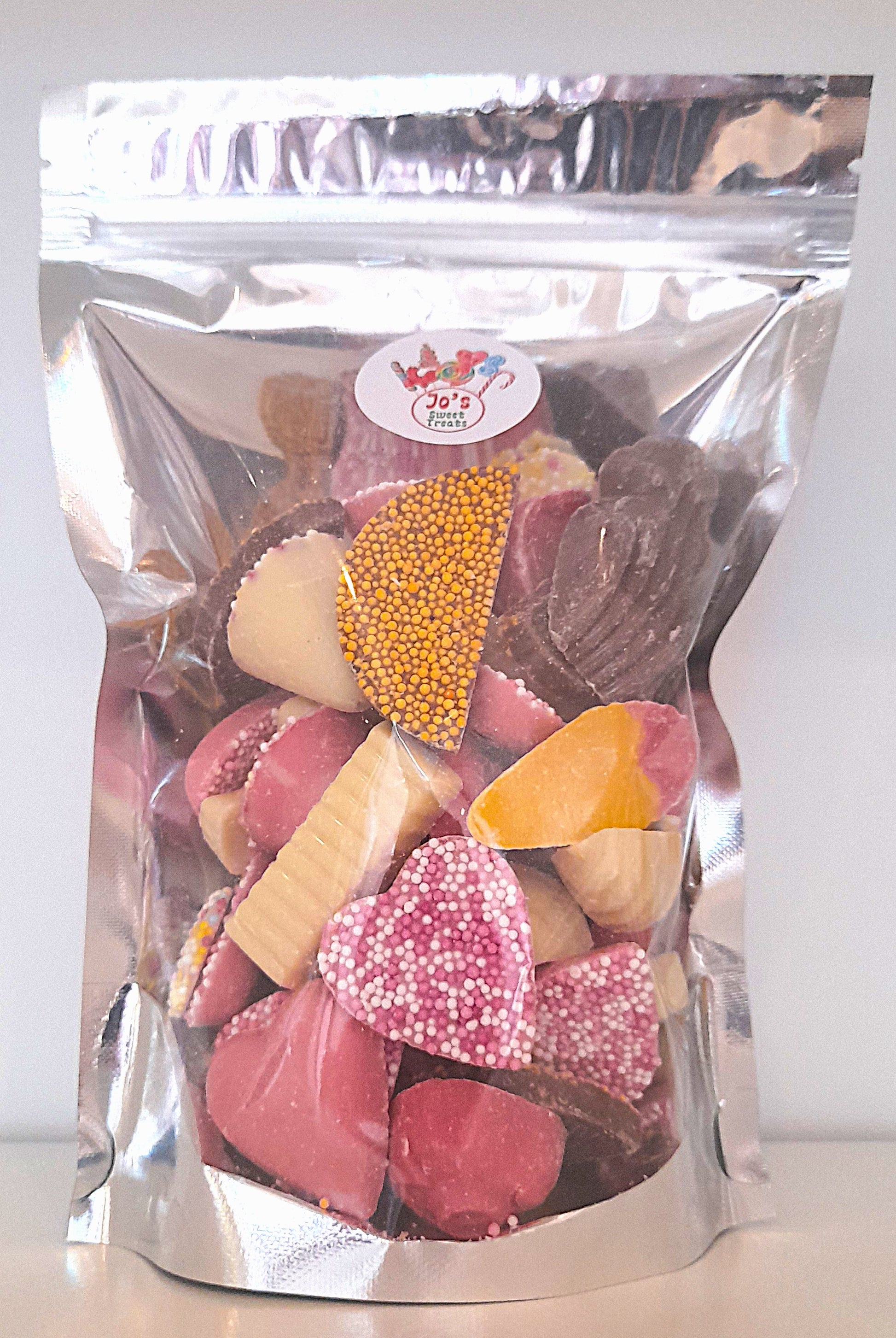 A pouch of chocolate mix with various shapes of chocolate pieces visible through the transparent packaging.