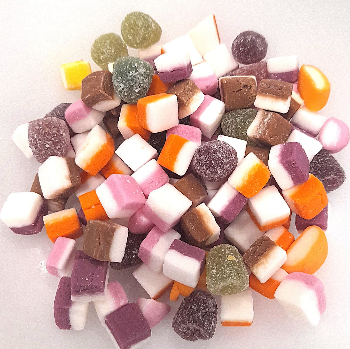 A variety of colorful candies in different shapes and flavors, commonly known as Dolly Mixture, arranged loosely in a pile.
