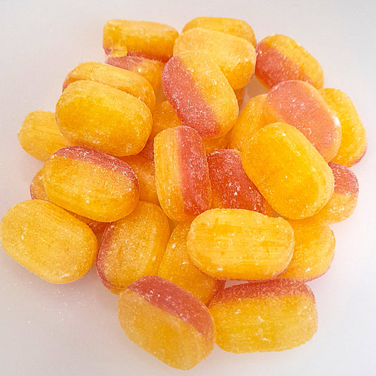 A pile of rhubarb and custard flavored candies, with a mix of yellow and pink colors.
