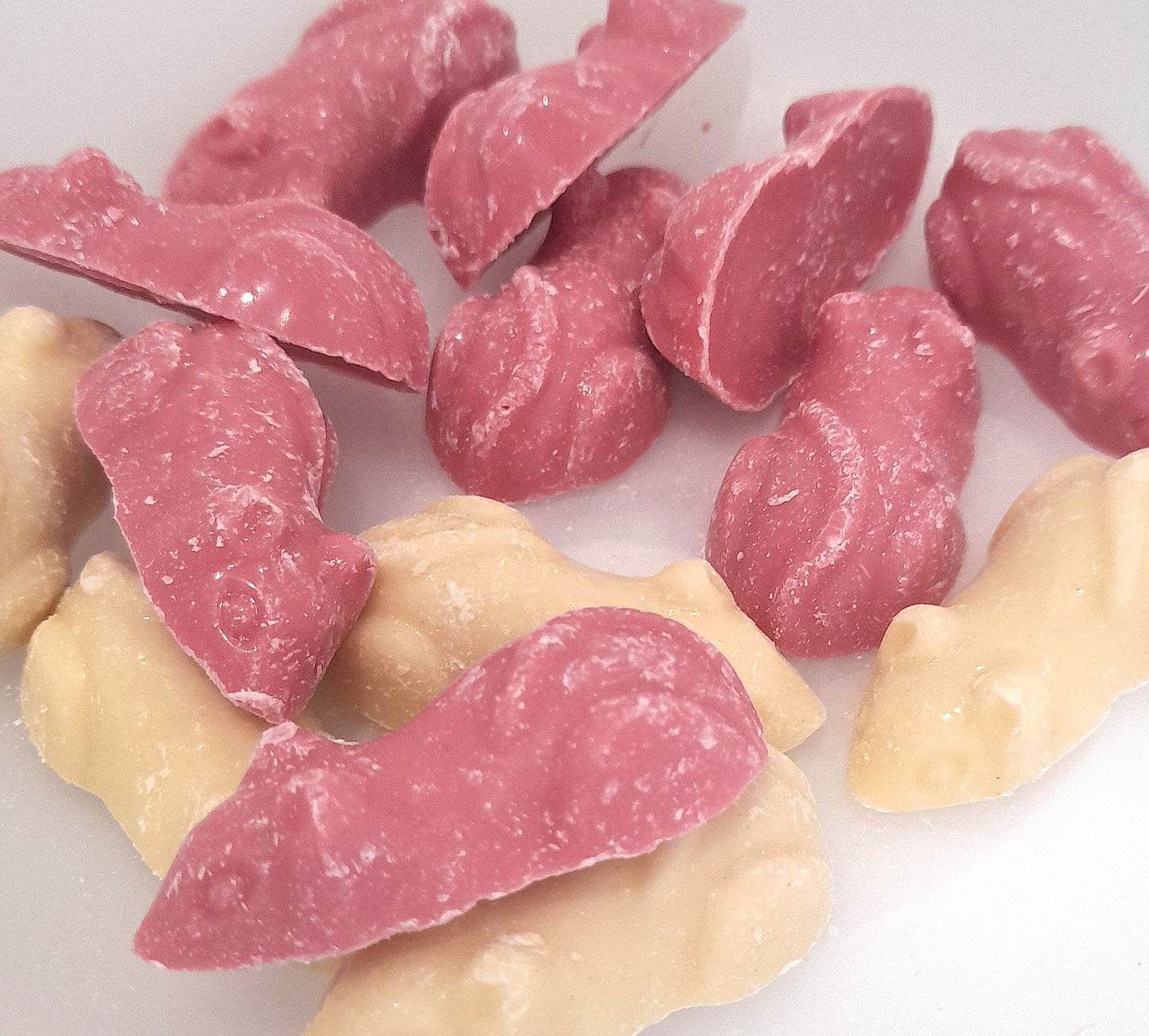 Strawberry and cream flavored candy pieces in the shape of mice, predominantly pink in color with white accents.