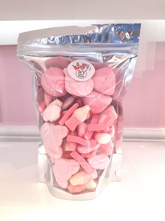 A clear plastic bag filled with various pink and white candy pieces, with a label showing the product name and a website.