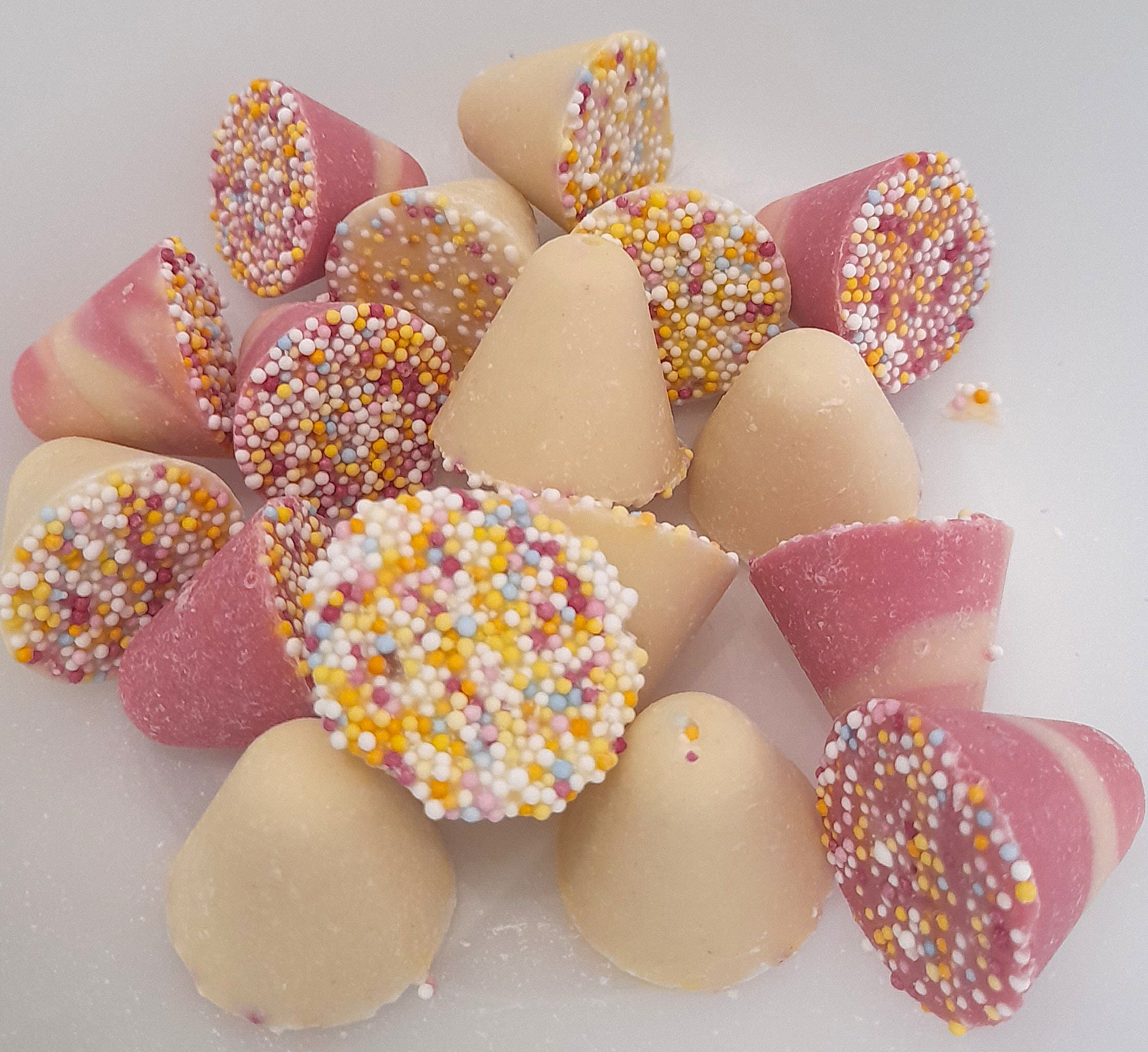 A bowl of spinning tops, which are chocolate pieces with strawberry and whipped cream flavor, and multicolored sprinkles on top.