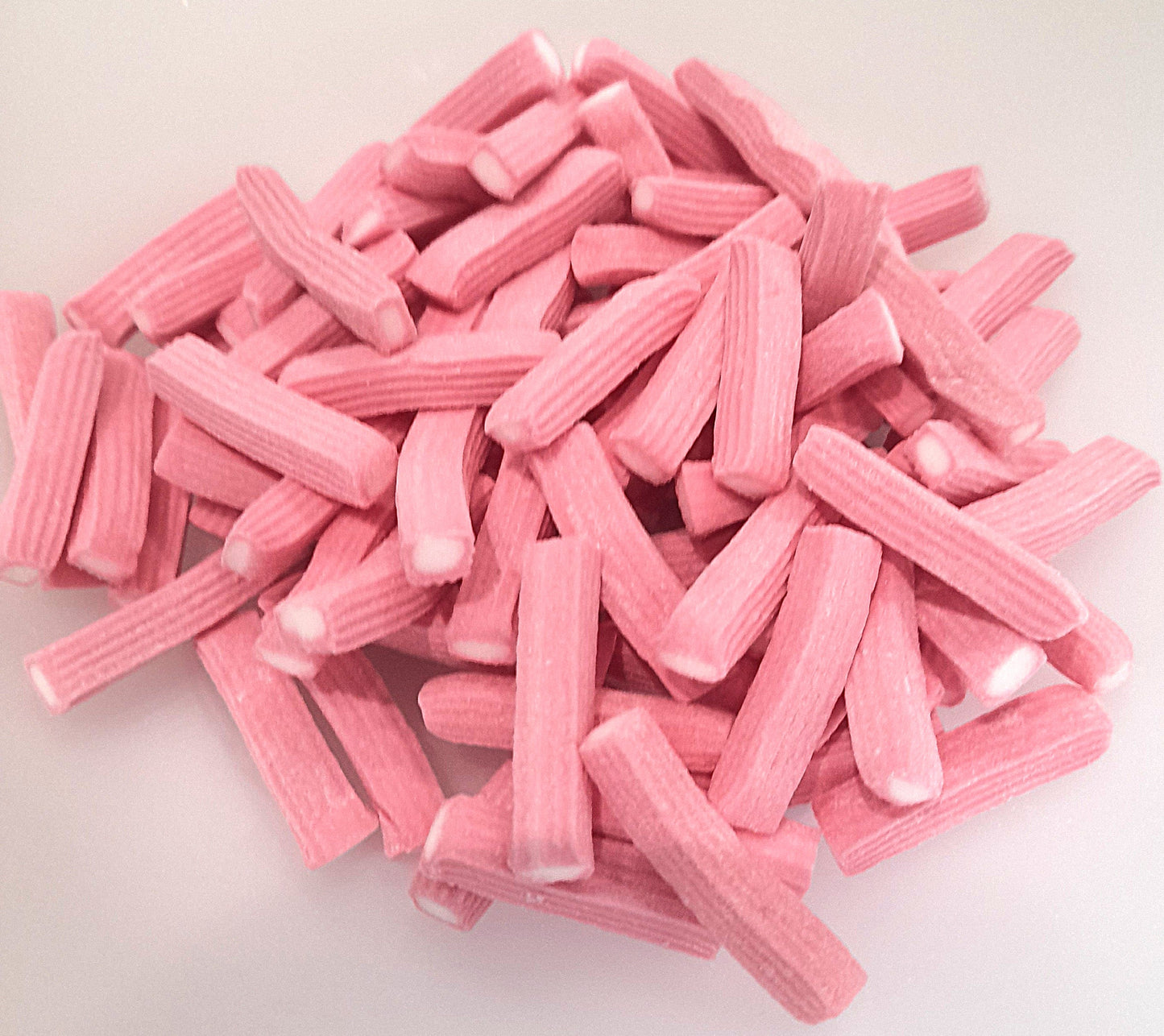 A pile of pink strawberry plank candy with white fondant filling.