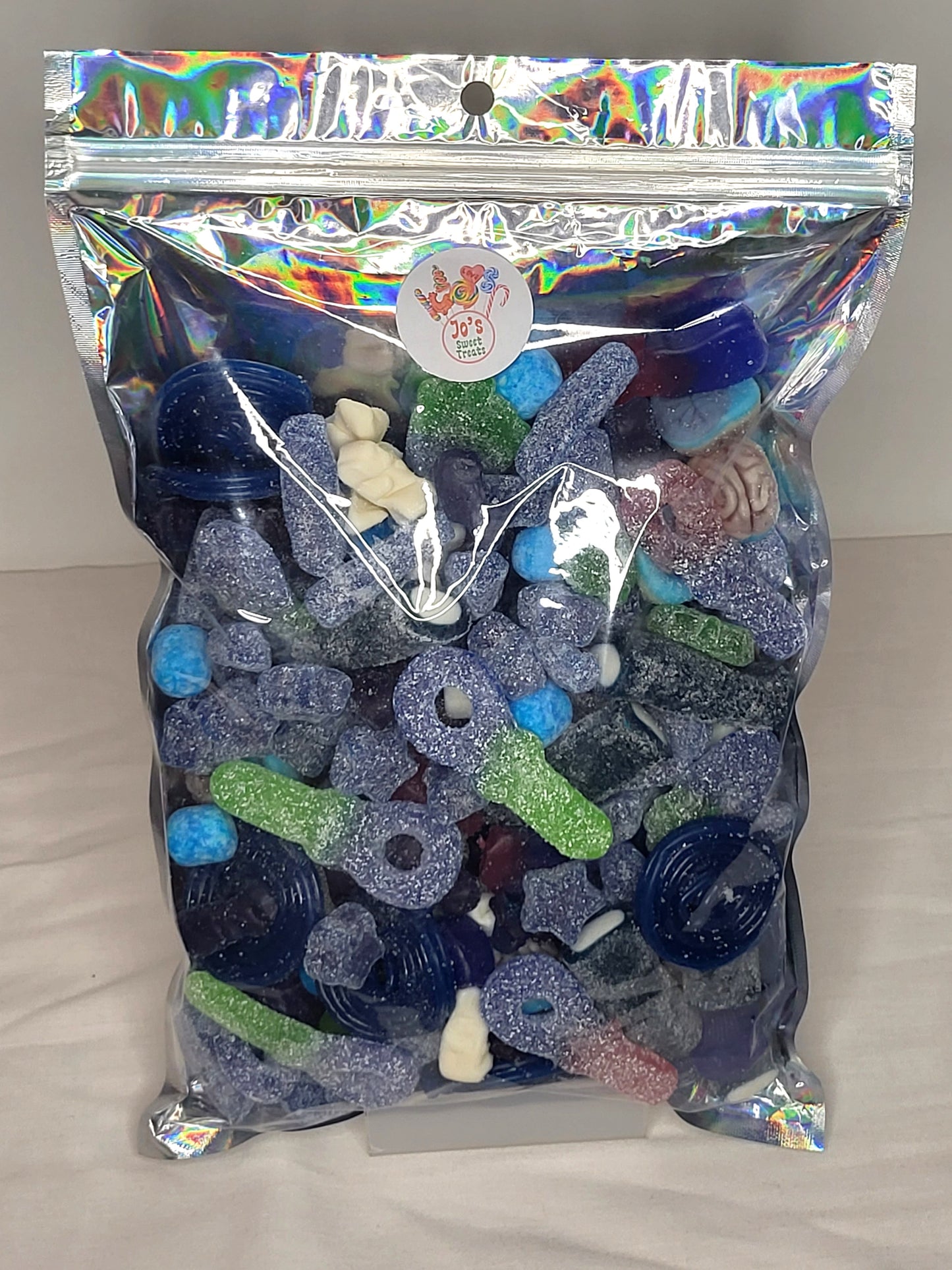 A resealable pouch containing a variety of blue sweets including fizzy tongue painters, blue raspberry wheels, and more.