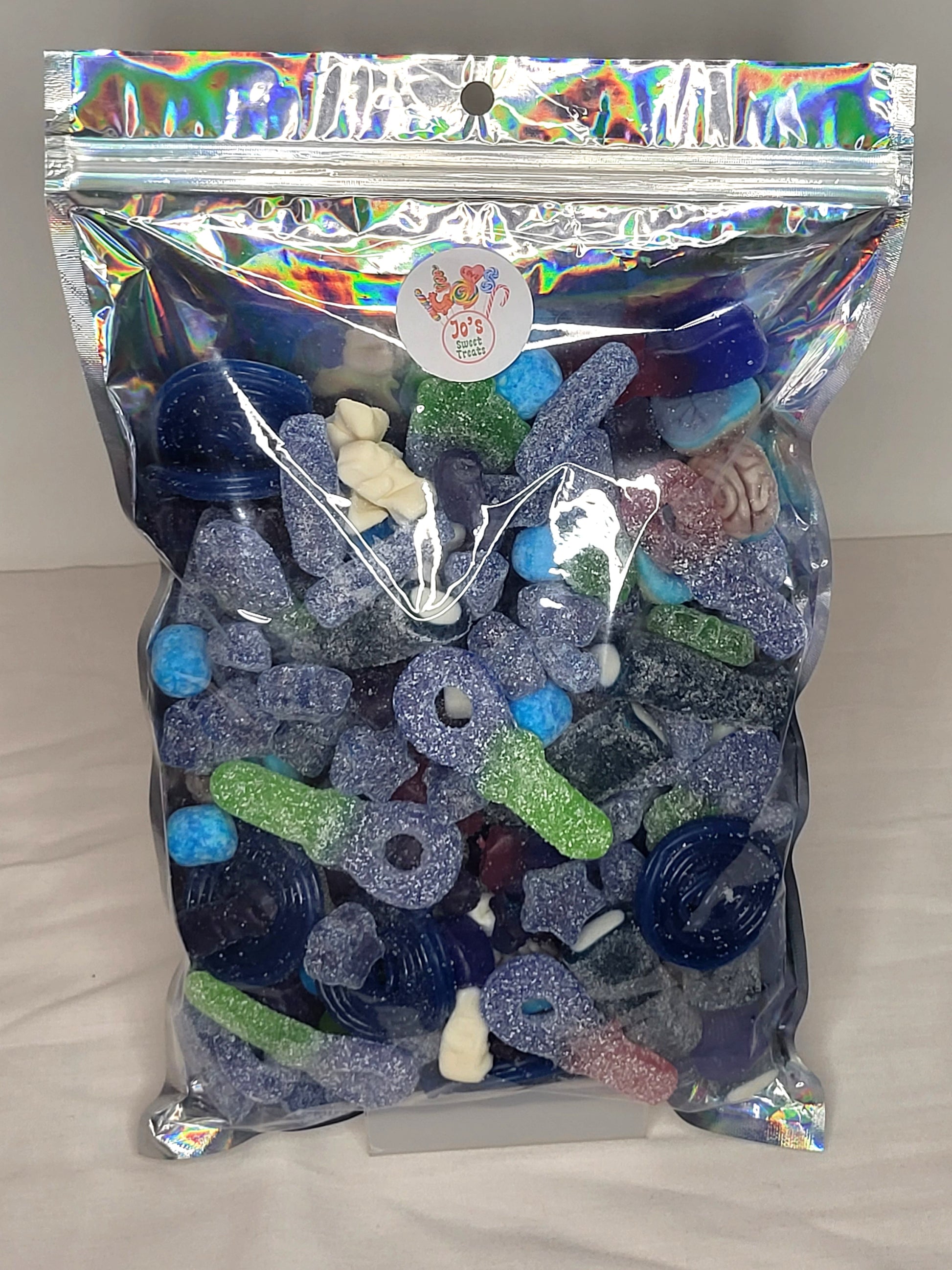 A resealable pouch containing a variety of blue sweets including fizzy tongue painters, blue raspberry wheels, and more.