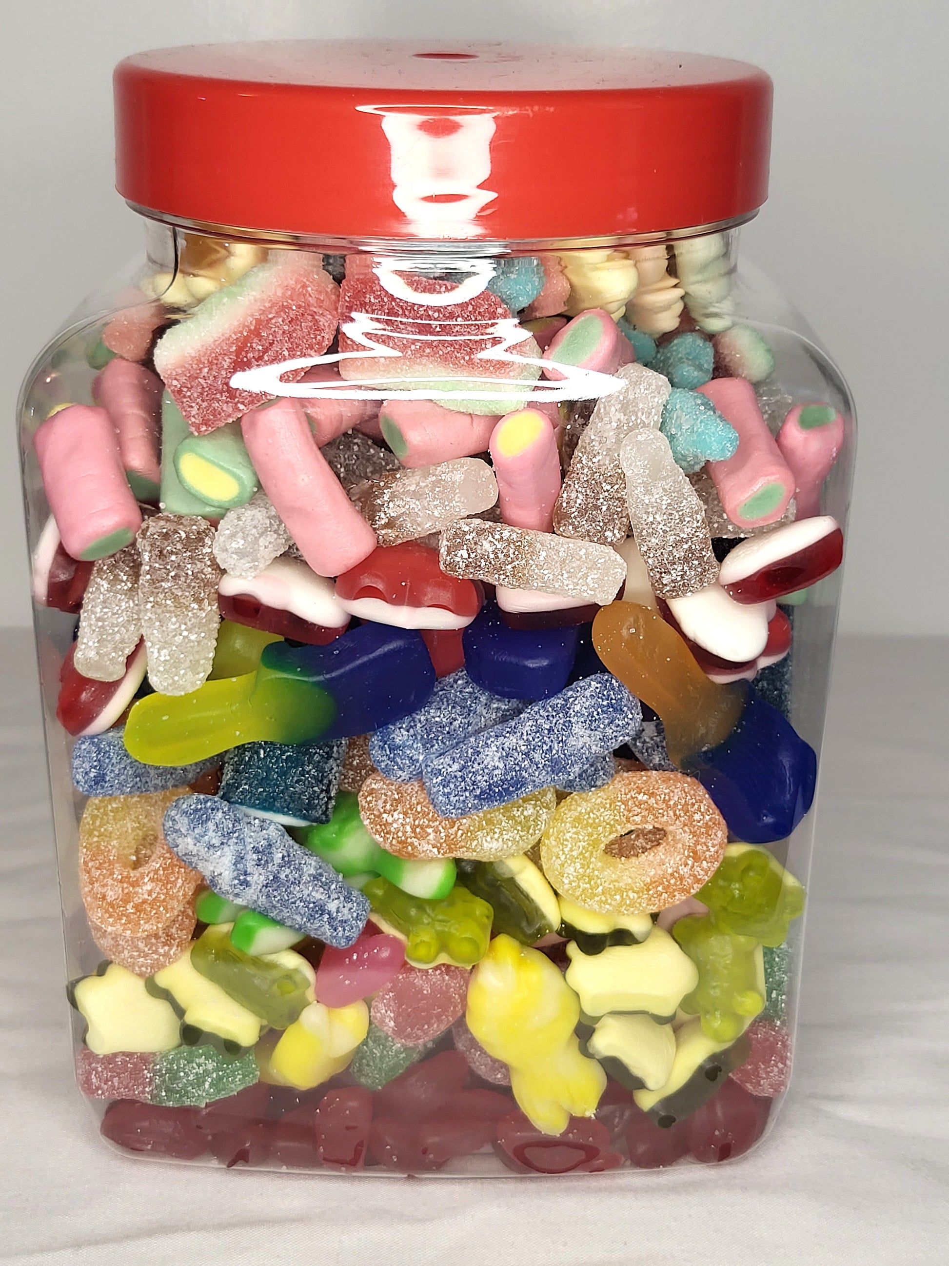 A medium-sized clear jar filled with a variety of colorful candies, sealed with a red lid.